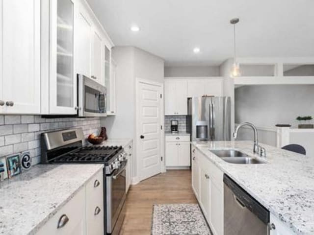 kitchen featuring pendant lighting, appliances with stainless steel finishes, sink, and white cabinetry