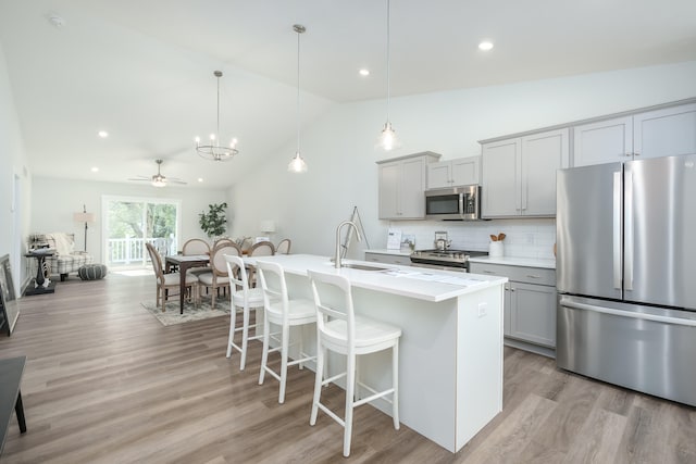 kitchen with hanging light fixtures, vaulted ceiling, gray cabinetry, and appliances with stainless steel finishes