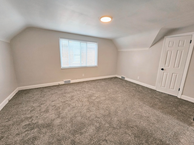 additional living space featuring lofted ceiling and dark colored carpet