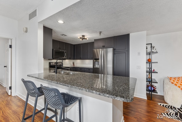 kitchen featuring kitchen peninsula, appliances with stainless steel finishes, dark hardwood / wood-style floors, and a textured ceiling