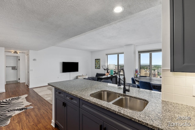 kitchen with gray cabinets, light stone counters, a textured ceiling, sink, and dark hardwood / wood-style flooring