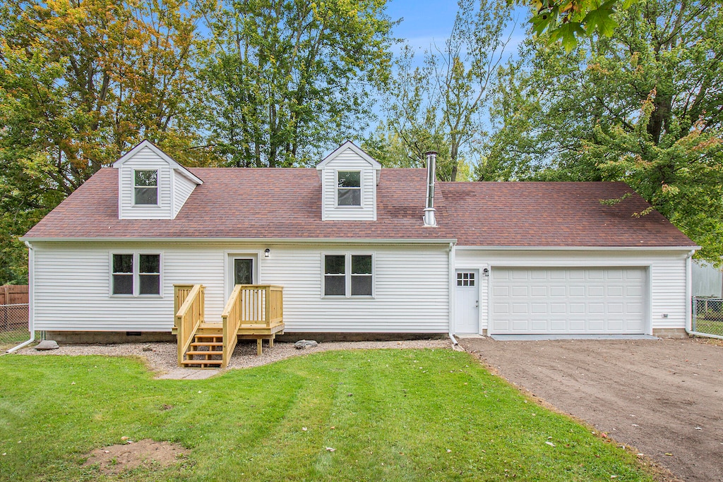 back of house featuring a garage, a deck, and a lawn