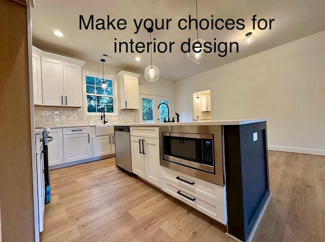 kitchen featuring light wood-type flooring, pendant lighting, stainless steel appliances, and white cabinets