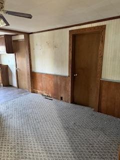 interior space featuring ornamental molding, wooden walls, and ceiling fan