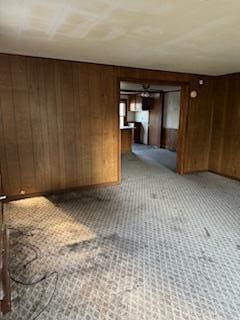 carpeted empty room featuring wood walls