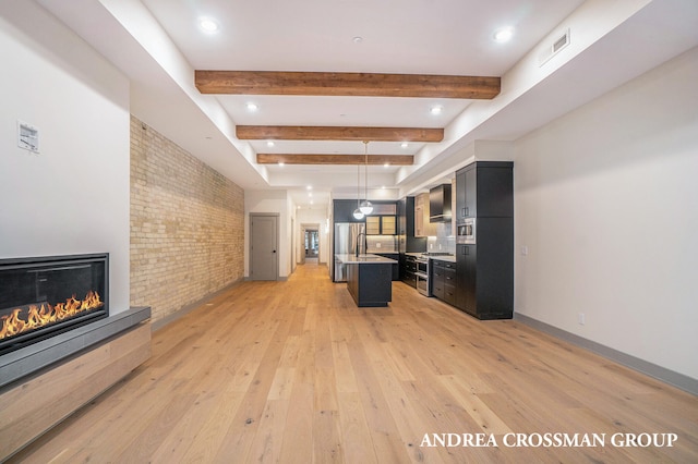 unfurnished living room featuring beam ceiling, sink, brick wall, and light wood-type flooring