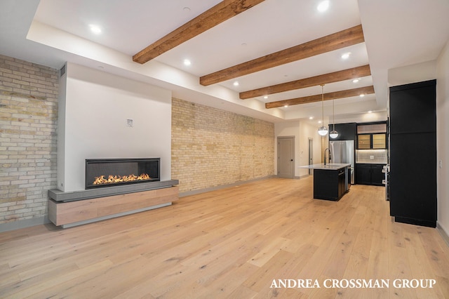 unfurnished living room with brick wall, beamed ceiling, and light hardwood / wood-style flooring