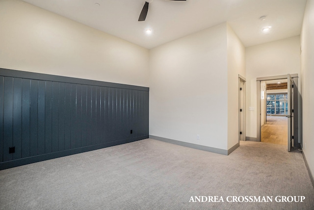 carpeted spare room featuring a high ceiling and ceiling fan