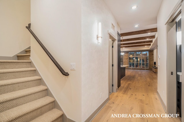 corridor featuring beam ceiling and light hardwood / wood-style flooring