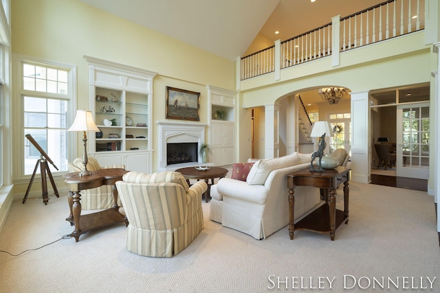 carpeted living room with high vaulted ceiling and decorative columns