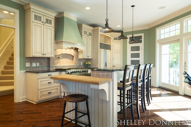 kitchen with a center island, a breakfast bar area, custom exhaust hood, and cream cabinetry