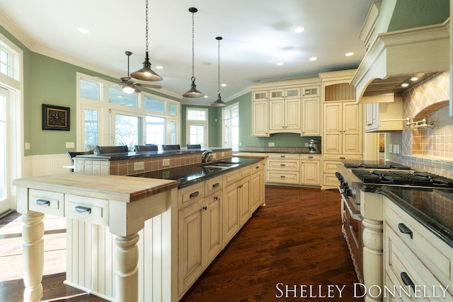 kitchen with cream cabinetry, hanging light fixtures, a center island with sink, and a kitchen bar