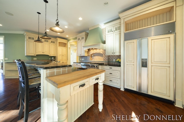 kitchen with a center island, custom exhaust hood, a kitchen breakfast bar, hanging light fixtures, and high quality appliances