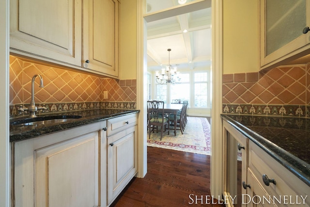 kitchen featuring crown molding, hanging light fixtures, sink, dark stone countertops, and dark hardwood / wood-style flooring