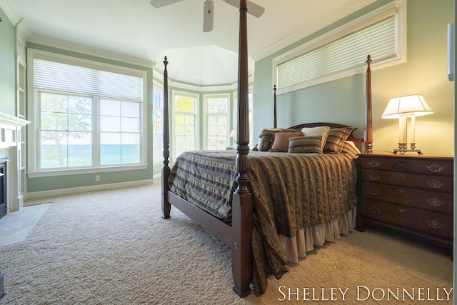 carpeted bedroom featuring crown molding, a tile fireplace, and ceiling fan