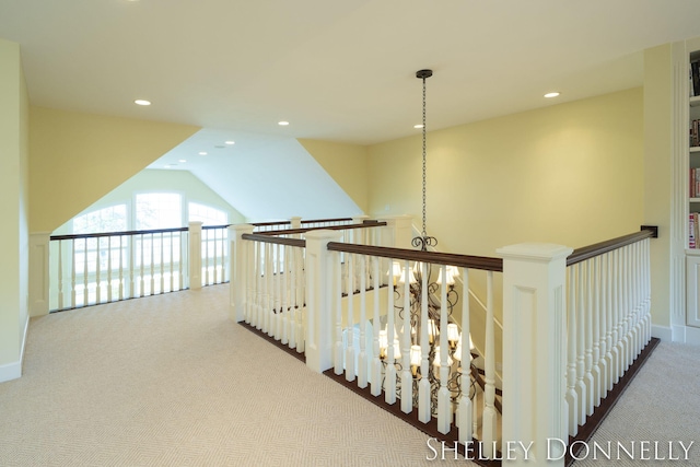 hallway featuring light carpet, lofted ceiling, and an inviting chandelier