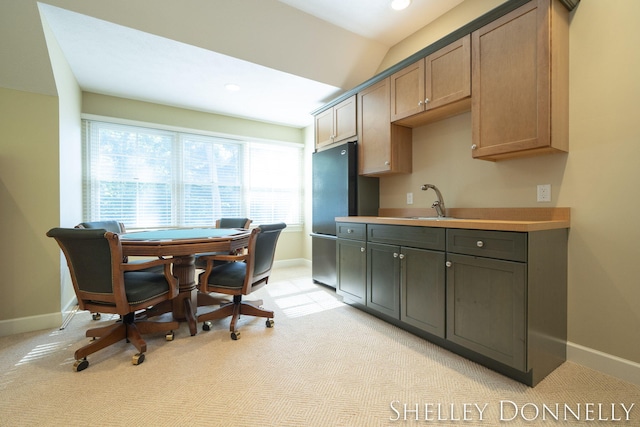 kitchen with sink, vaulted ceiling, black fridge, and light carpet