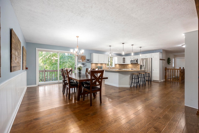 dining area with dark wood-style floors, a notable chandelier, and a textured ceiling