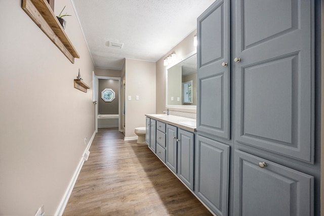 full bathroom with a textured ceiling, toilet, wood finished floors, visible vents, and vanity