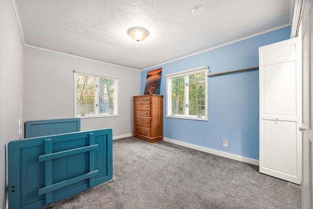 carpeted bedroom with a textured ceiling, crown molding, and baseboards