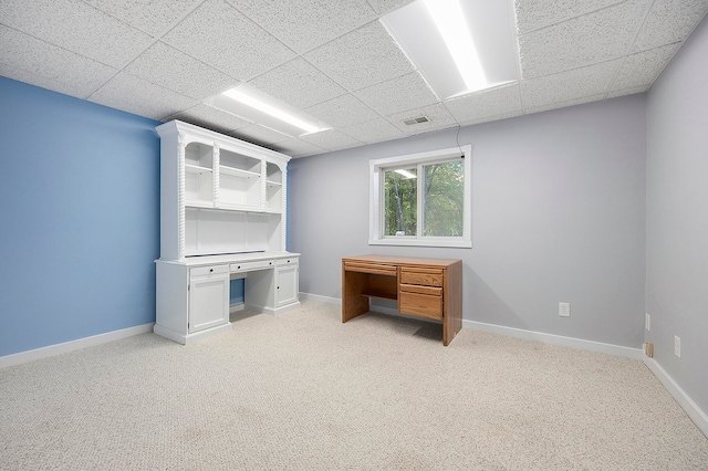 unfurnished office with baseboards, a drop ceiling, visible vents, and light colored carpet