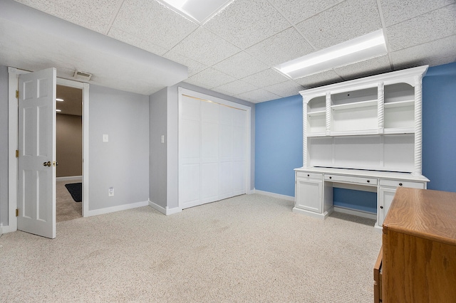 unfurnished office with light carpet, visible vents, baseboards, and a drop ceiling