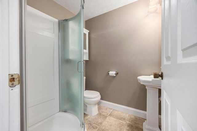 bathroom featuring a shower with door, toilet, a textured ceiling, tile patterned flooring, and baseboards