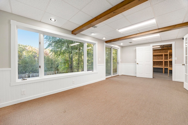 empty room with recessed lighting, a wainscoted wall, carpet flooring, and a drop ceiling