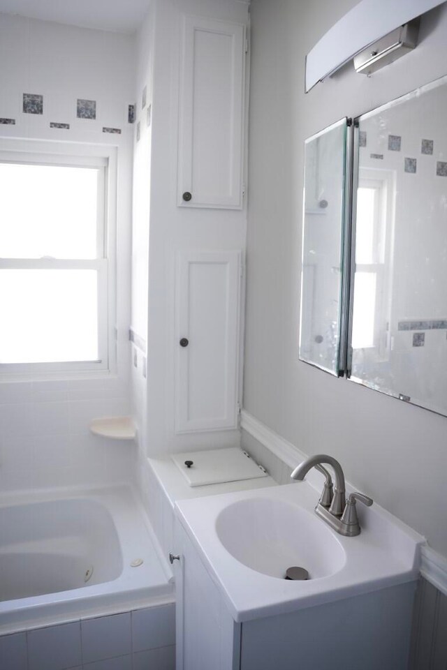 bathroom with tiled tub and vanity