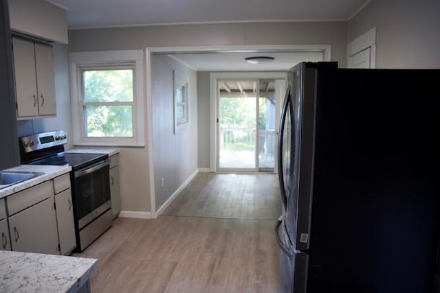 kitchen featuring light wood-type flooring, stainless steel electric range, black fridge, and a healthy amount of sunlight