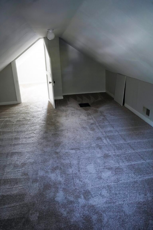 additional living space featuring dark carpet and lofted ceiling