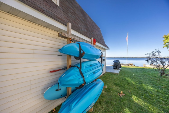 view of dock with a lawn and a water view