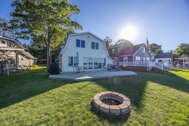 back of property featuring a yard, an outdoor fire pit, and a wooden deck