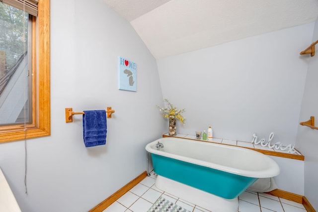 bathroom with tile patterned flooring, vaulted ceiling, a textured ceiling, and a bathing tub