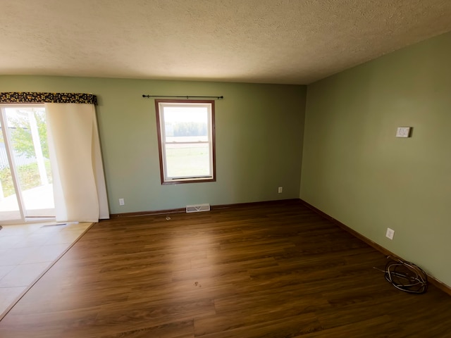 spare room with a textured ceiling and dark hardwood / wood-style flooring