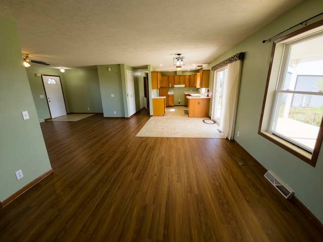 unfurnished living room featuring ceiling fan, hardwood / wood-style floors, and a textured ceiling