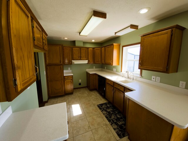 kitchen with a textured ceiling, black dishwasher, light tile patterned flooring, and sink