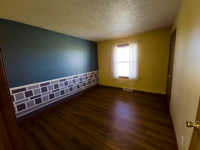 spare room with a textured ceiling and dark wood-type flooring