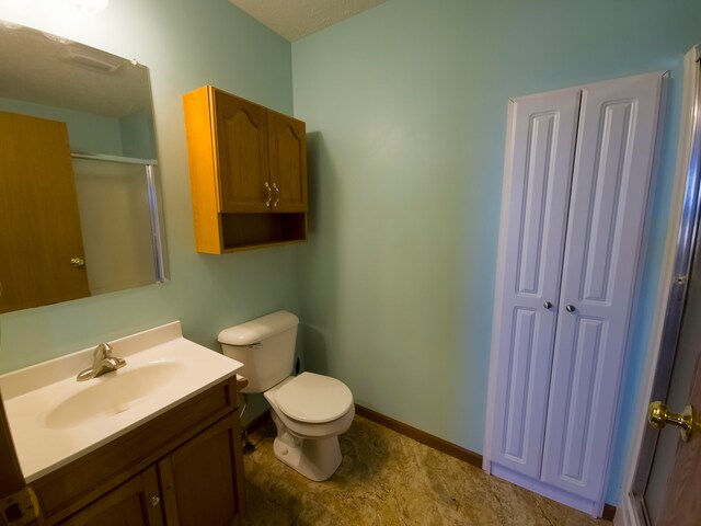 bathroom with a textured ceiling, an enclosed shower, vanity, and toilet