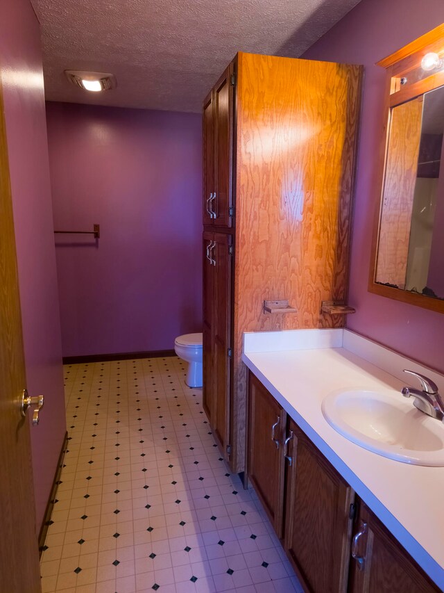 bathroom with a textured ceiling, vanity, and toilet