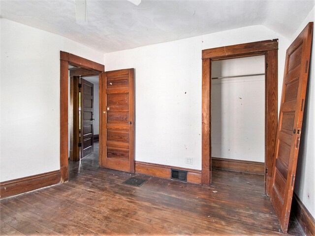 unfurnished bedroom with vaulted ceiling, ceiling fan, a closet, and dark hardwood / wood-style floors