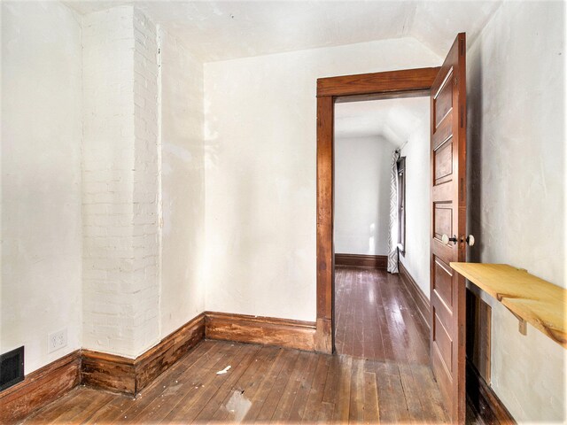 unfurnished room featuring dark wood-type flooring and vaulted ceiling