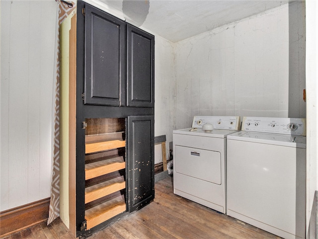 clothes washing area with washer and dryer, wooden walls, cabinets, and dark hardwood / wood-style floors