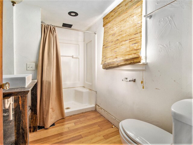 bathroom featuring toilet, wood-type flooring, and a shower with shower curtain