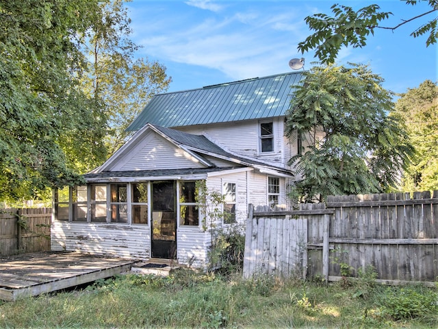 rear view of house featuring a sunroom and a wooden deck