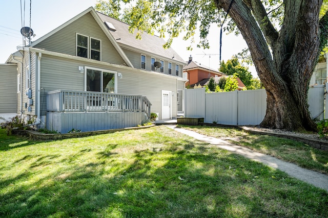 rear view of property featuring a yard and a wooden deck