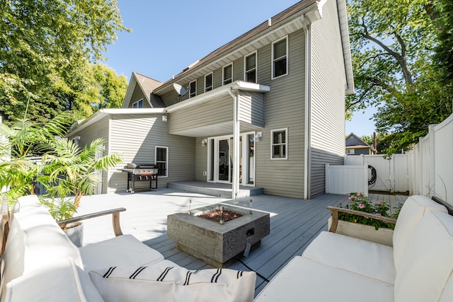 back of property featuring a wooden deck and an outdoor living space with a fire pit