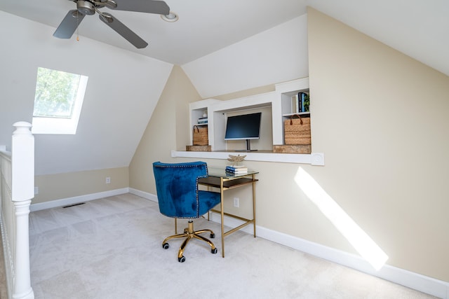 office area featuring ceiling fan, lofted ceiling with skylight, and light carpet