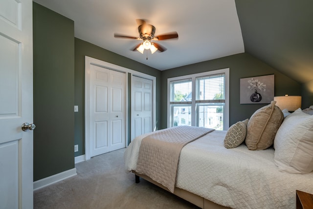 carpeted bedroom with ceiling fan, vaulted ceiling, and two closets