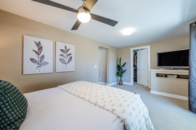 carpeted bedroom with a closet, a walk in closet, and ceiling fan